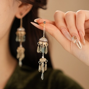 Close-up of vintage gold tassel earrings with grey beads and pearls worn by a model