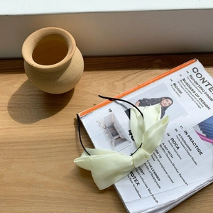 Gros plan d'un serre-tête à nœud en tissu jaune pâle sur un magazine sur surface en bois