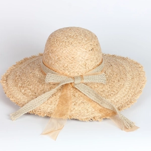 Close-up of natural raffia straw sun hat with layered bow detailing and woven textures