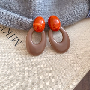 Detail of retro oval earrings with orange mica bead and coffee-colored resin rings