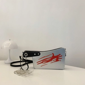 Close-up of a silver cleaver bag with red splatter pattern and black handle strap