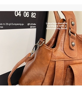 Detailed close-up of premium dark metal hardware and rivets on a brown leather tote bag