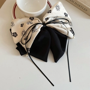 Détail de la pince à cheveux élégante à nœud camélia avec perles et longs rubans en soie