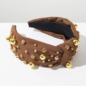 Detail of knot headband with gold beads and pink rhinestones on brown fabric