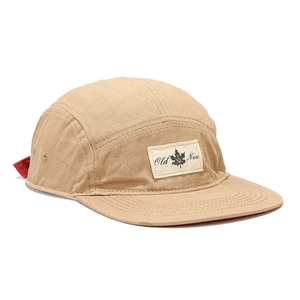 Khaki 5-panel camper hat with flat brim and maple leaf patch in a 45-degree view