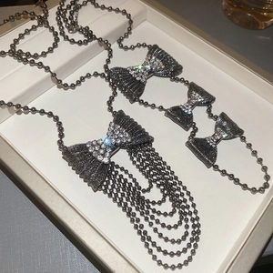 Macro detail of gunmetal bow pendant necklace with sparkling rhinestones and bead tassels