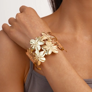 Macro detail of gold layered floral bracelet with textured metallic flower petals