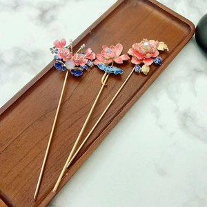 Three Chinese pearl flower hairpins on a wooden tray with elegant traditional floral design