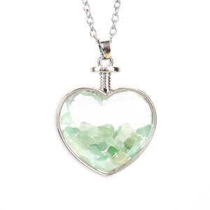 Detailed view of a heart-shaped glass bottle pendant filled with green natural stones