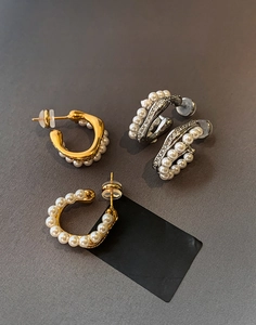 Macro view of C-shaped earrings with pearls and rhinestones in gold and silver finish