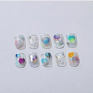 Detail of handmade press-on nails featuring 3D aurora hearts and glitter on clear base