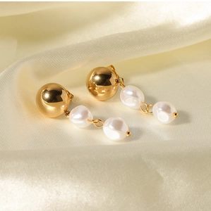 Detailed macro of gold metal ball studs with elegant baroque pearl tassel drop earrings