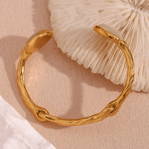 Detail of branch texture gold cuff bracelet featuring cream oval gemstone accents