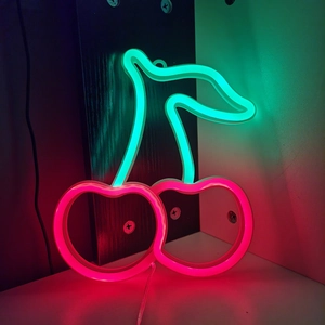 Close-up of cherry neon sign with green LED leaves and red glowing fruit decor