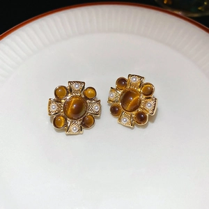 Detailed view of vintage gold cross-shaped earrings with faux pearl and cat eye stone