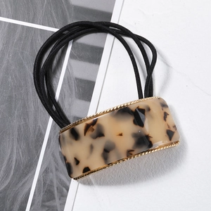 Close-up of tortoiseshell resin hair tie with gold trim and elastic band details