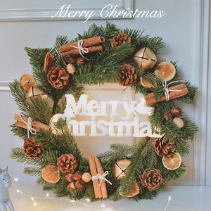 Artificial Christmas wreath with pine needles, cones, cinnamon sticks, and Merry Christmas sign