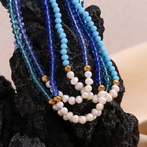 Detail of blue crystal beads and freshwater pearls draped over textured volcanic rock