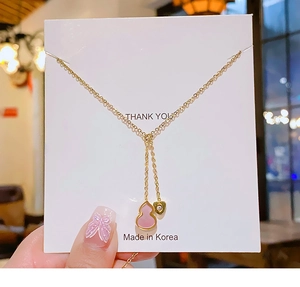Close-up of a 18k gold plated titanium necklace with pink gourd and heart pendants