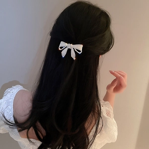 Vue arrière d'un mannequin portant une barrette nœud en strass avec une robe en dentelle