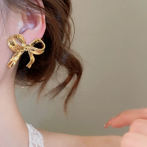 Gros plan de boucles d'oreilles nœud dorées avec finition métallique sur un mannequin