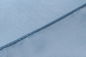 Macro detail of light blue satin fabric showing fine texture and professional stitching