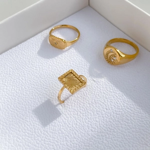 Detailed shot of celestial gold rings featuring sun and moon engravings with zircons