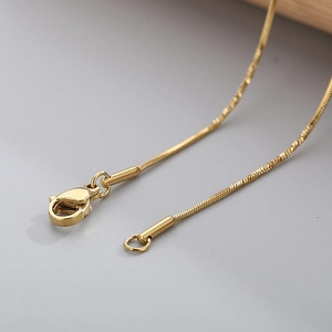 Detailed close-up of golden stainless steel snake chain showing secure lobster clasp