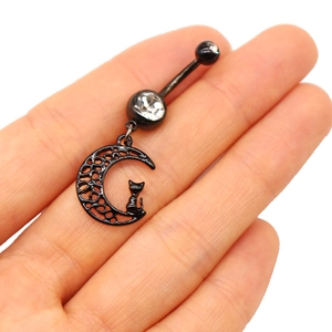 Vue macro d'un piercing de nombril lune et chat noir avec gemmes claires sur la main