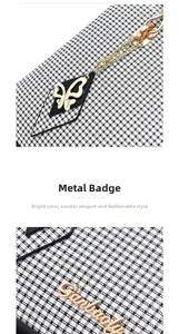 Detail view of gold butterfly pendant and metallic brand logo on black-white plaid handbag