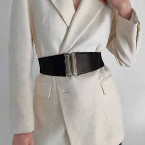 Detail of a vintage black wide corset belt with matte silver buckle on a white blazer