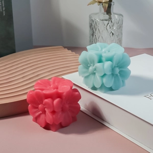 Primer plano detallado de velas artesanales con forma de flores esféricas rosa y azul