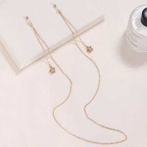 Détail de la chaîne de lunettes dorée avec étoiles et boucles en silicone sur beige