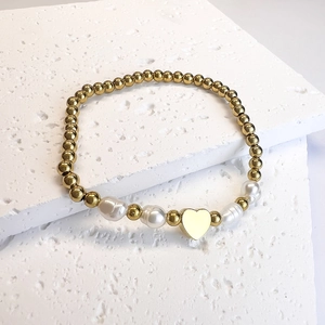 Detailed shot of golden bead bracelet featuring freshwater pearls and heart charm