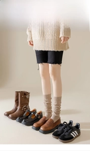 Détail de chaussettes hautes en maille beige avec mocassins marron et plusieurs chaussures