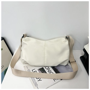 Detail view of large cream minimalist dumpling bag with textured pleated surface and wide strap