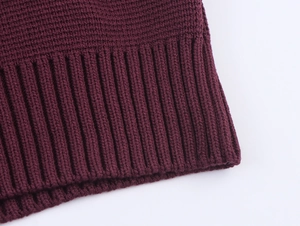 Detail shot of the burgundy knitted fabric texture with ribbed hem on the sleeve cuff