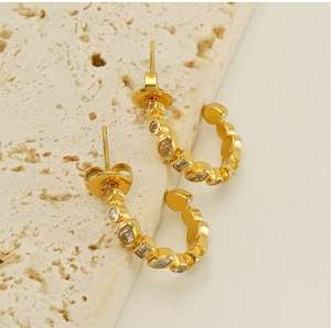Close-up of C-shaped 18k gold plated earrings with sparkling cubic zirconia inlays