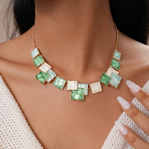 Detail of a geometric enamel necklace with green and white squares in golden frame