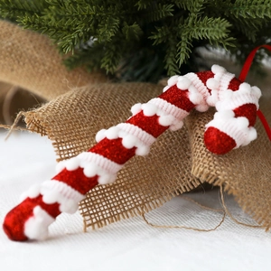 Glittery red and white foam candy cane ornament on rustic burlap with pine branches