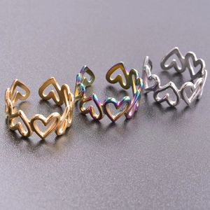 Three minimalist stainless steel open rings with heart patterns in gold, silver, and rainbow