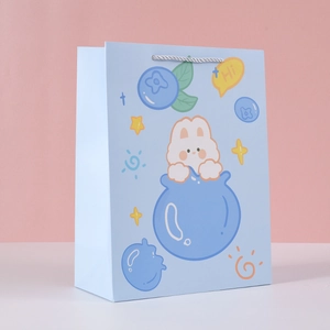 Detail of light blue starry sky gift bag featuring cute white rabbit and woven handles