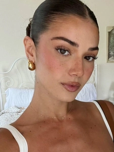 Gros plan de boucles d'oreilles boules dorées et d'un collier avec pendentif lettre D
