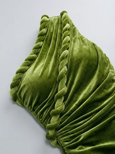 Detail of olive green velvet dress showing intricate twisted trim and pleated fabric texture