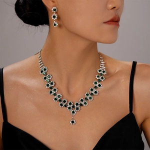 Detail of sunflower necklace and earrings set with green gemstones and shiny diamonds
