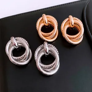 Intertwined triple-hoop earrings in gold and silver finish with textured surface