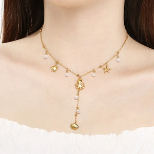 Detail of gold ocean charm necklace with pearls and sea creature pendants on model