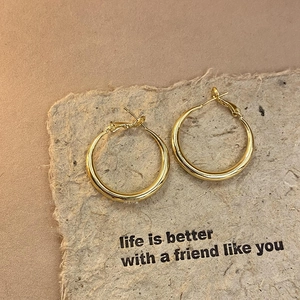 Close-up of golden twisted geometric hoop earrings on a textured paper background