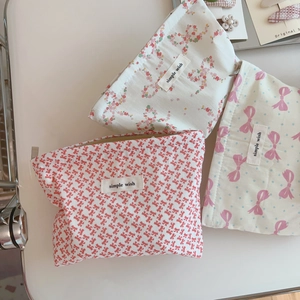 Three cotton makeup pouches with floral and bow patterns featuring zipper closures