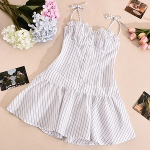Flat lay of a striped summer dress featuring tie-up straps, buttons, and ruffle hem details